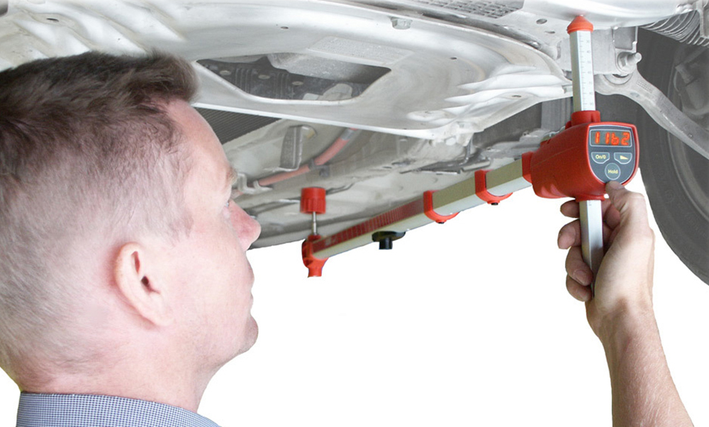 A person is standing under a car and they are measuring with Allvis.